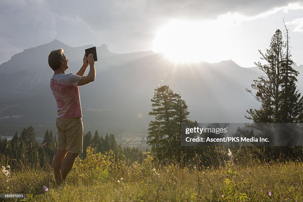 Man takes picture with digital tablet, mtn meadow