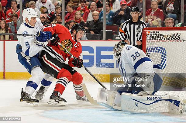 Goalie Ben Bishop of the Tampa Bay Lightning blocks the shot attempt by Jonathan Toews of the Chicago Blackhawks as Sami Salo of the Lightning pushes...