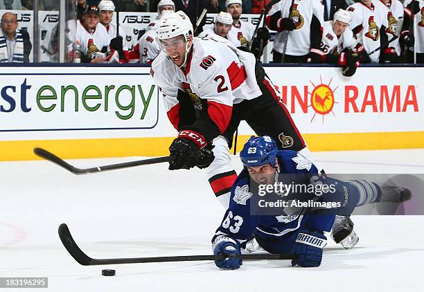 Dave Bolland of the Toronto Maple Leafs gets tripped by Jared Cowen of the Ottawa Senators during the home opener at the Air Canada Centre October 5,...