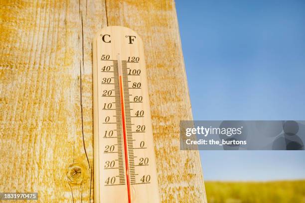 thermometer at a wooden wall at beach - meteorology stockfoto's en -beelden