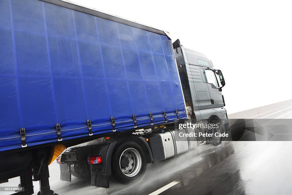 Blue lorry driving on wet road