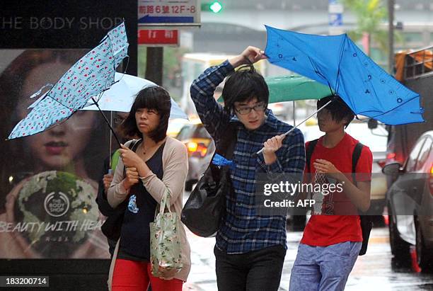 Pedestrians walk through strong winds and rain caused by Typhoon Fitow in Taipei on October 6, 2013. Taiwan on October 5 issued a warning over...