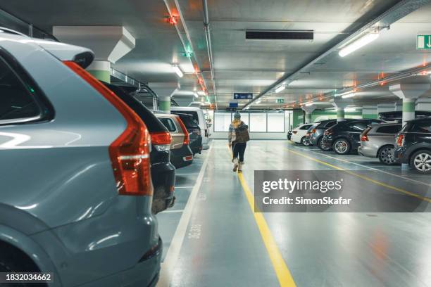 vista posteriore della donna che cammina al parcheggio dell'auto - parcheggiare foto e immagini stock