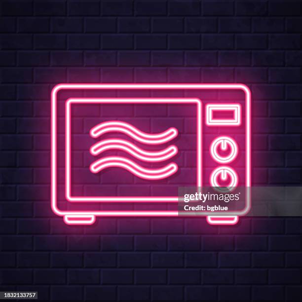 microwave oven. glowing neon icon on brick wall background - microwave button clip art stock illustrations