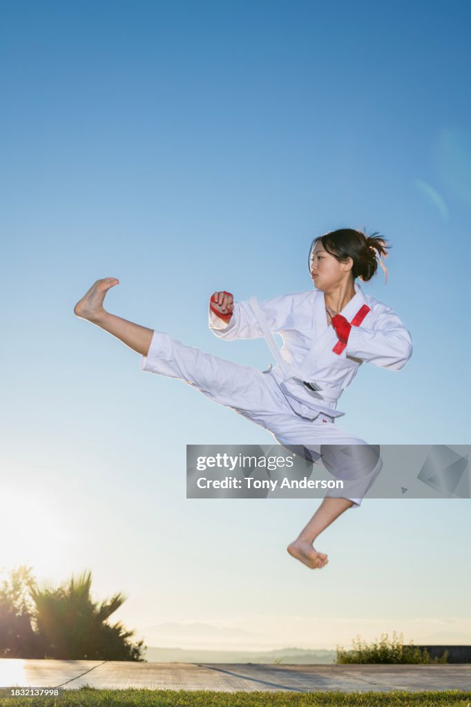 Teenage girl martial artist doing flying kick