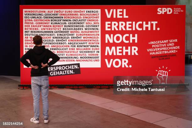 A participant stands in front of a SPD Political campaign billboard as he attends the SPD federal congress on December 8, 2023 in Berlin, Germany....