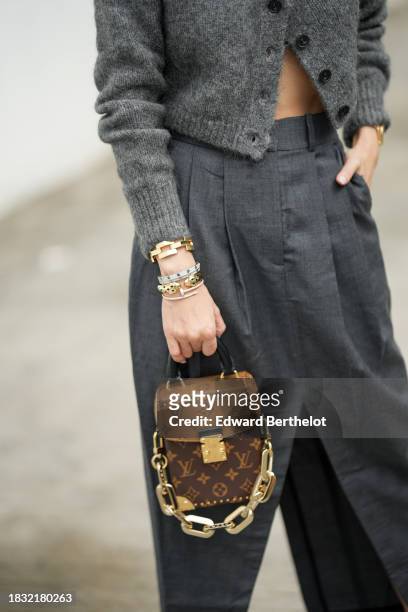Heart Evangelista wears a brown Louis Vuitton monogram printed bag, gray suit pants, a golden Cartier bracelet, during a street style fashion photo...