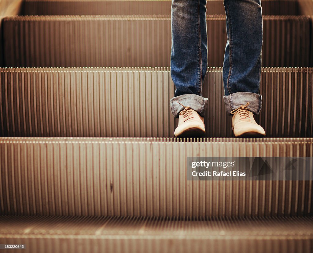 Legs standing on escalator