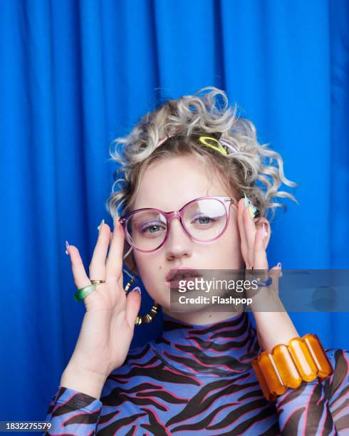 portrait of genz woman standing in front of a blue curtain background. - reading glasses stock pictures, royalty-free photos & images
