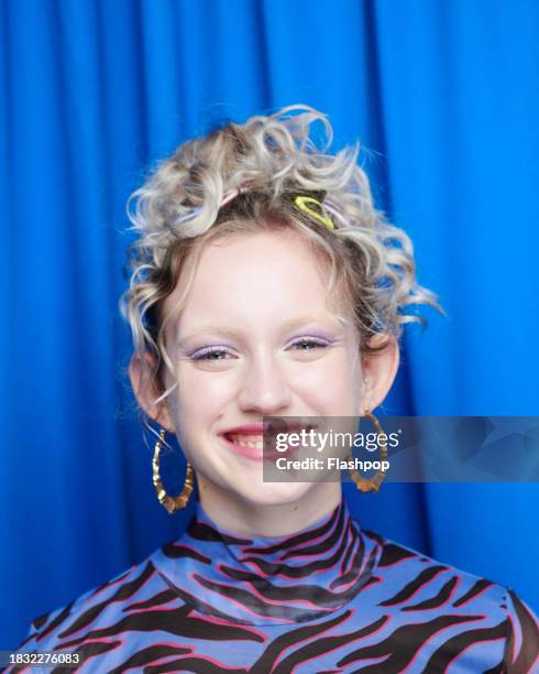 portrait of genz woman standing in front of a blue curtain background. - woman smiling white background stock pictures, royalty-free photos & images