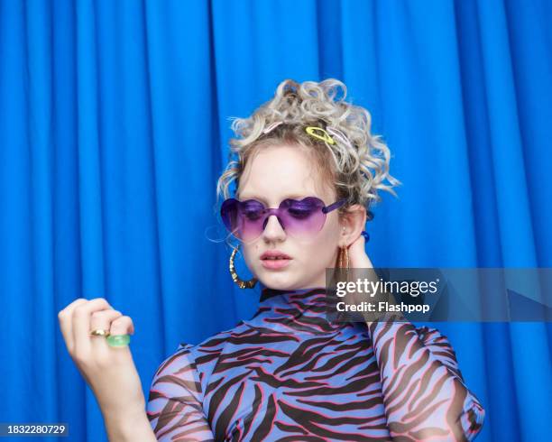 portrait of genz woman standing in front of a blue curtain background. - design by hand series celebration stock pictures, royalty-free photos & images