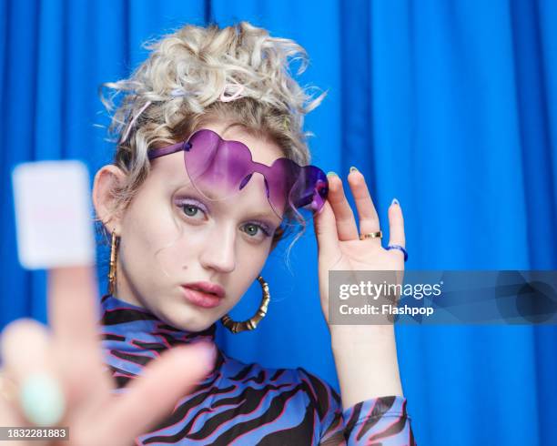 portrait of genz woman standing in front of a blue curtain background. - woman smiling white background stock pictures, royalty-free photos & images