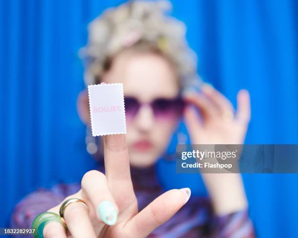 portrait of genz woman standing in front of a blue curtain background. - woman smiling white background stock pictures, royalty-free photos & images