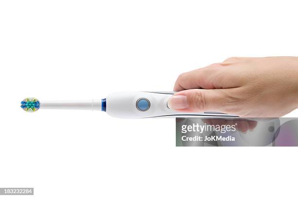 electric toothbrush in her hand - toothbrush stock pictures, royalty-free photos & images