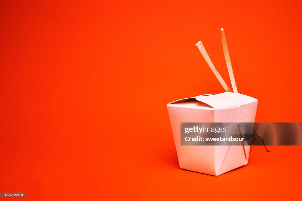 Chinese takeout container with chopsticks, isolated on red