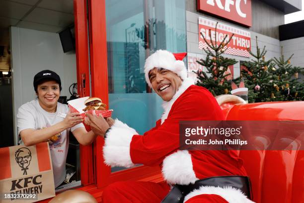 In this image released on December 11 Chris Kamara visits a KFC's Sleigh Thru to launch the Stuffing Stacker Burger in Slough,England. To celebrate...