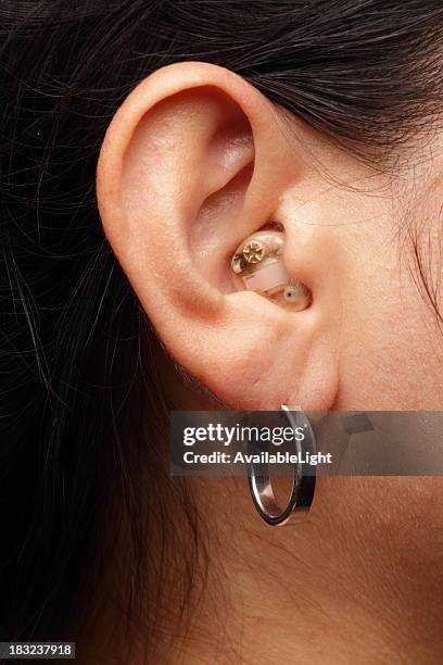 hearing aid in woman's ear - hearing aids stock pictures, royalty-free photos & images