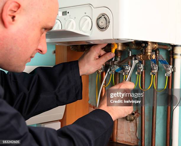 plumber installing a boiler - boilers stock pictures, royalty-free photos & images