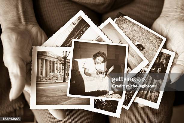 elderly woman holding a collection of old photographs - geschiedenis stockfoto's en -beelden