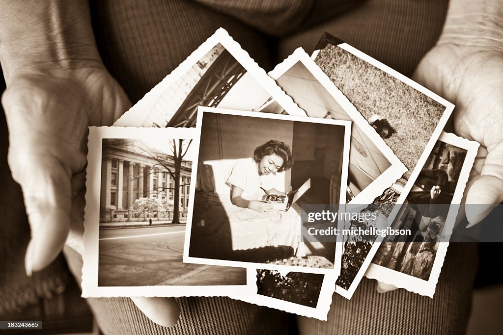 Elderly woman holding a collection of old photographs