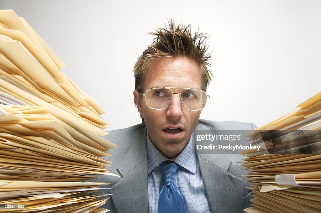 Employé de bureau Looks stupéfait entre la pile de documents
