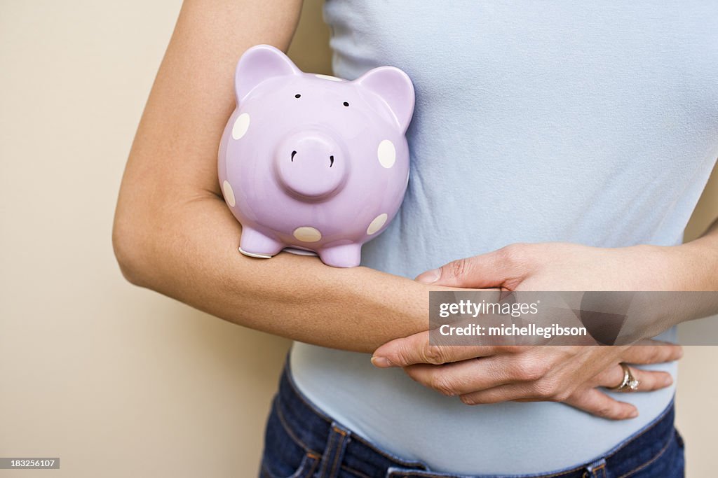 Frau hält ihr Sparschwein Einsparungen in den Armen