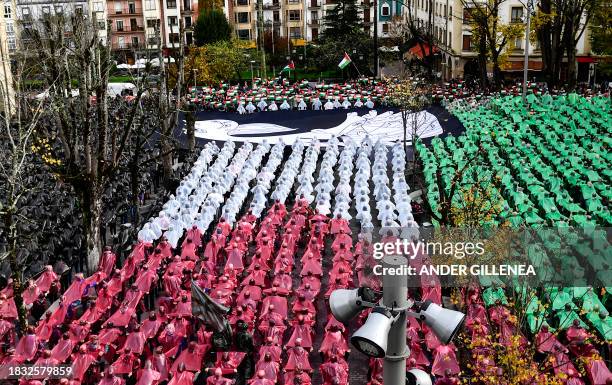 People create a human mosaic representing the Palestinian flag and hold a canvas with a detail of Pablo Picasso's masterpiece "Gernica" depicting a...