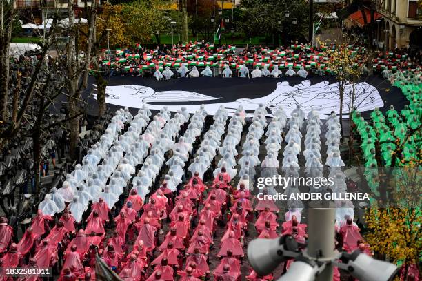 People create a human mosaic representing the Palestinian flag and hold a canvas with a detail of Pablo Picasso's masterpiece "Gernica" depicting a...