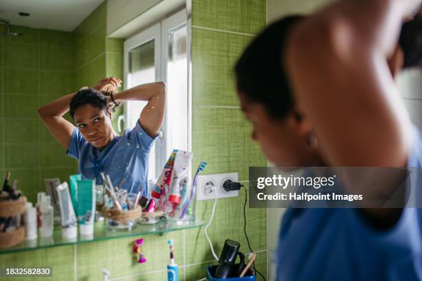 female nurse or doctor getting ready for work in the morning, brushing hair, making ponytail in bathroom. morning hair and skincare before leaving house, dressed in scrubs. - ponytail stock pictures, royalty-free photos & images