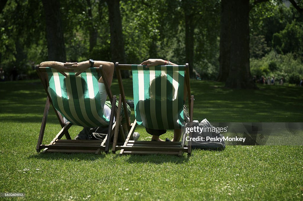 Two People Relaxing in Striped Deck Chairs London Park