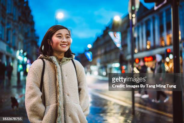 cheerful teenage girl walking in the street while exploring in a town at dusk - road signal stock pictures, royalty-free photos & images