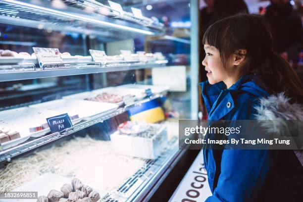 lovely cheerful girl looking into a chocolate shop window - retail equipment stock pictures, royalty-free photos & images