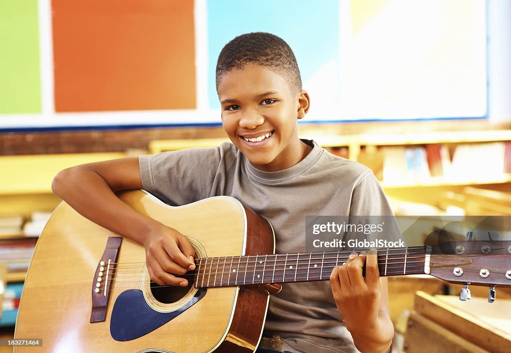 Young boy with acoustic guitar in classroom