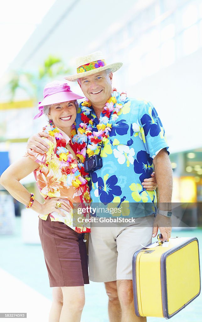 Couple in floral clothing with luggage embracing at an airport