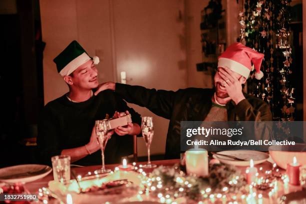 friends exchanging gifts at a christmas dinner table - exchanging gifts stock pictures, royalty-free photos & images