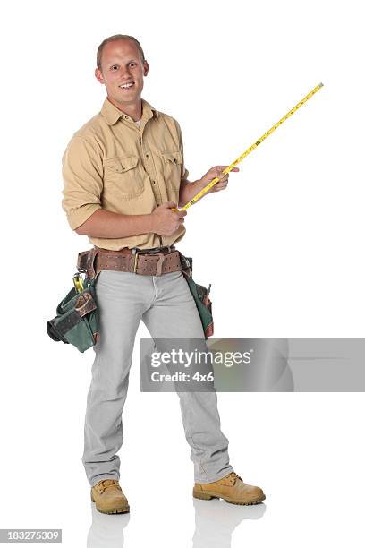 carpenter holding a tape measure - builder standing isolated stock pictures, royalty-free photos & images