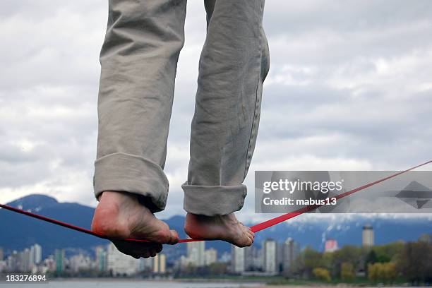 man balancing on a red tightrope in bare feet - tightrope stockfoto's en -beelden