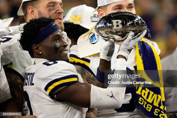 Mike Sainristil of the Michigan Wolverines holds up the trophy after winning the Big Ten Championship against the Iowa Hawkeyes at Lucas Oil Stadium...