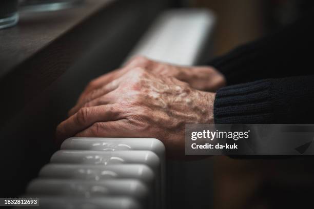 cold at home. a man tries to warm his hands on a radiator - cold temperature stock pictures, royalty-free photos & images