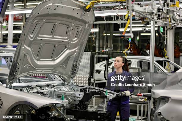 Member of BMW's manufacturing staff inspects a vehicle's finish as he works at the body shop finish during German Chancellor Olaf Scholz visits the...