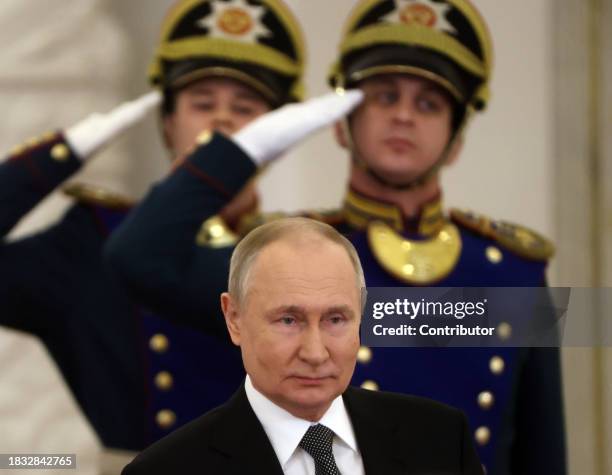 Russian President Vladimir Putin leaves the hall of the Grand Kremlin Palace as offficers of the Presidential Regiment look on during the award...