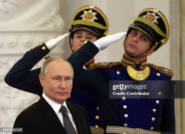 Russian President Vladimir Putin leaves the hall of the Grand Kremlin Palace as offficers of the Presidential Regiment look on during the award...