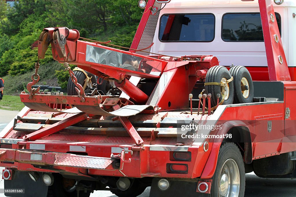 Close-up of red tow truck in a road near trees