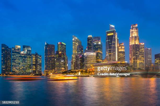 singapur marina bay glitzernde wolkenkratzer beleuchtet in der abenddämmerung mit blick auf die uferpromenade - singapore river stock-fotos und bilder