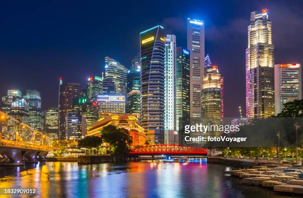 glittering skyscrapers illuminated at night overlooking singapore river marina bay - global stock pictures, royalty-free photos & images