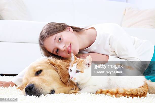 jolie fille allongée sur le tapis blanc avec les animaux de compagnie. - chat et chien photos et images de collection