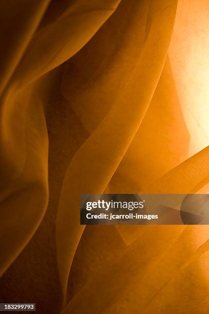fabric flows in golden light - gold satin fabric stock pictures, royalty-free photos & images