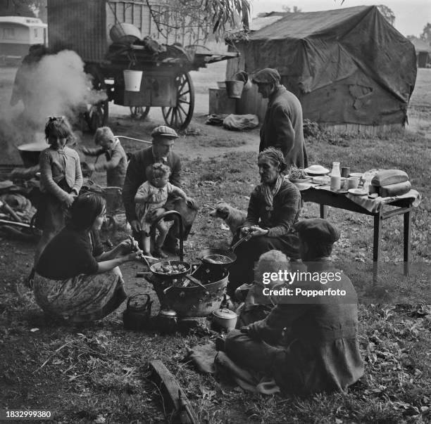 Mrs Liza Fletcher prepares the evening meal for her Romani family on a brazier fire outside their caravan on a site in England on 4th July 1946.