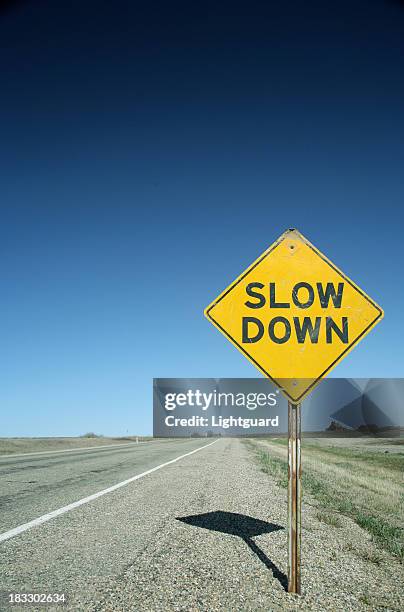 sign on flat prairie road avverte conducente di rallentare - lentezza foto e immagini stock