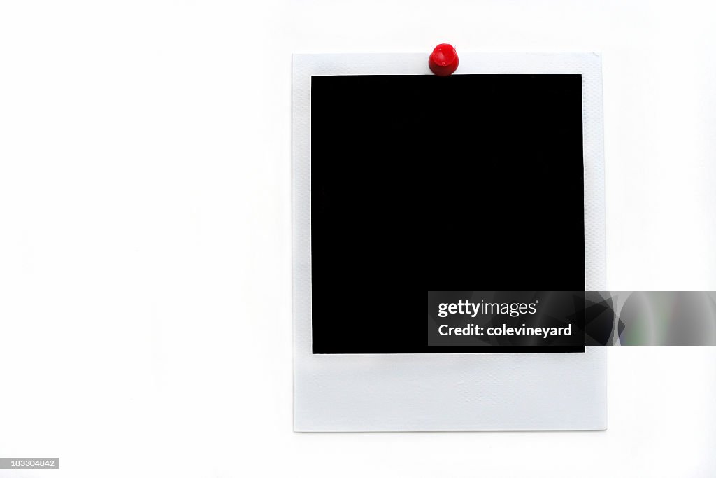 Instant photo held up by a red thumbtack